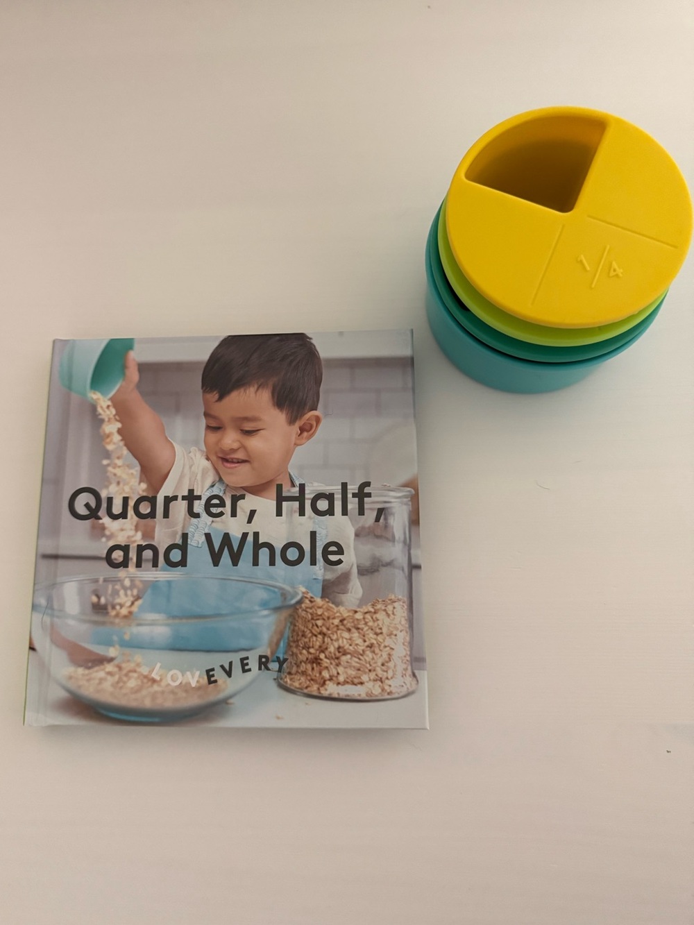 Lovevery measuring cup and book quarter, half and whole